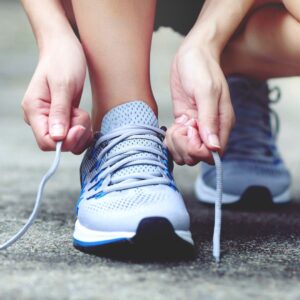 Person lacing up their tennis shoes.