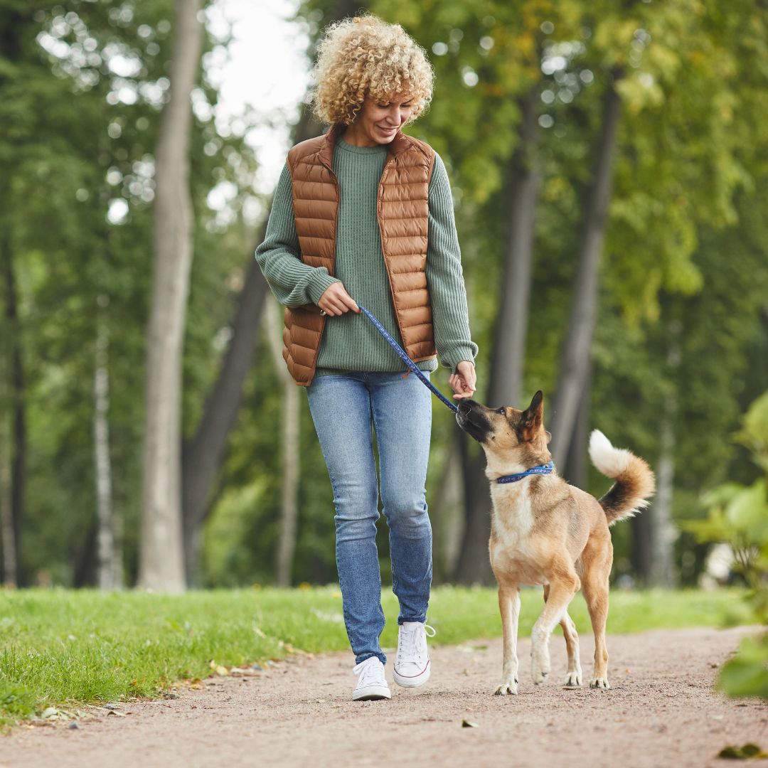 woman walking her dog happily on a nice day